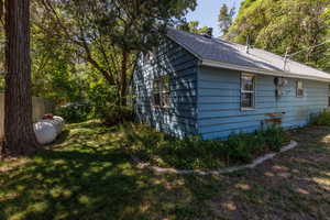 View of side of property featuring a yard and roof with shingles