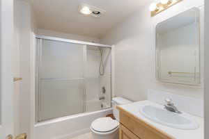 Bathroom with vanity and bath / shower combo with glass door