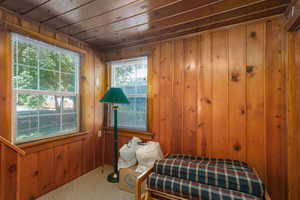 Carpeted bedroom featuring wood walls and wooden ceiling