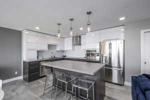 Kitchen featuring modern cabinets, stainless steel appliances, a breakfast bar area, tasteful backsplash, and white cabinets