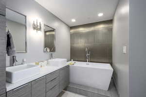Bathroom with a soaking tub, double vanity, tile patterned floors, and recessed lighting