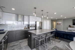 Kitchen with modern cabinets, a kitchen bar, tasteful backsplash, a center island, and stainless steel appliances