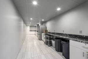 Kitchen with a drop ceiling, recessed lighting, dark stone counters, freestanding refrigerator, and white cabinetry