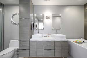 Bathroom with double vanity, recessed lighting, and a tub to relax in