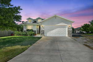 View of front facade featuring driveway, a garage, and stone siding