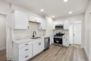 Kitchen with appliances with stainless steel finishes, light wood-style floors, white cabinets, light countertops, and recessed lighting