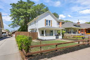 View of front of home featuring a porch, a fenced front yard, and roof with shingles