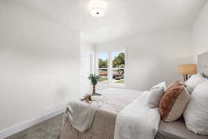 Carpeted bedroom featuring baseboards and a textured ceiling