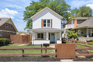 View of front of home featuring covered porch, a shingled roof, a gate, and a fenced front yard