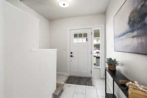 Doorway with marble look tiles and a textured ceiling