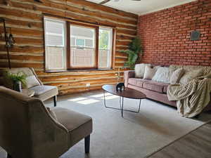 Living room featuring rustic walls, a ceiling fan, brick wall, and wood finished floors