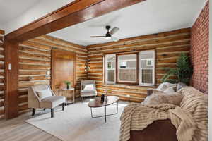 Sitting room featuring a ceiling fan, wood finished floors, rustic walls, and a textured ceiling