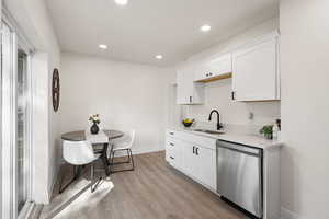 Kitchen with dishwasher, white cabinets, recessed lighting, light wood-style floors, and light stone counters
