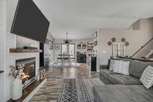Living room with wood finished floors, lofted ceiling, and a fireplace