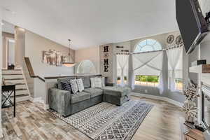 Living area with wood finished floors, vaulted ceiling, and a glass covered fireplace