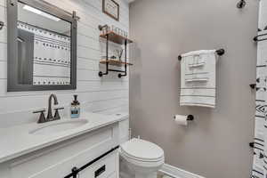 Bathroom with vanity, a shower with shower curtain, and wooden walls