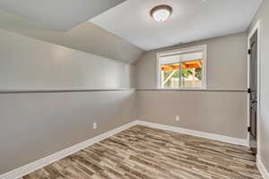 Additional living space featuring wood finished floors and vaulted ceiling