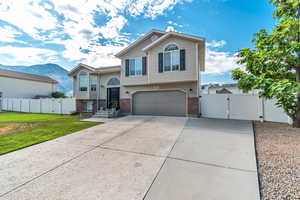 View of front of property featuring a gate, brick siding, a garage, concrete driveway, and a mountain view