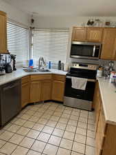Kitchen featuring appliances with stainless steel finishes, light countertops, light tile patterned floors, and a textured ceiling