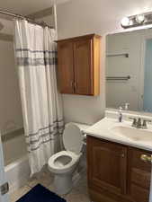 Bathroom featuring vanity, shower / bath combo with shower curtain, light tile patterned floors, and a textured ceiling