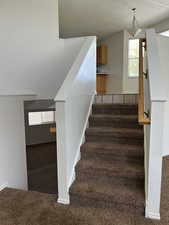 Stairs with healthy amount of natural light, carpet floors, and a textured ceiling