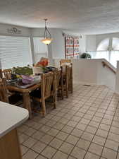 Dining room with light tile patterned floors, plenty of natural light, and a textured ceiling