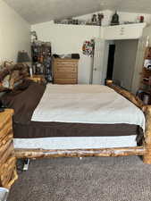 Bedroom with vaulted ceiling, carpet, and a textured ceiling