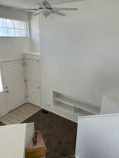 Entrance foyer featuring healthy amount of natural light, light tile patterned flooring, light carpet, and ceiling fan