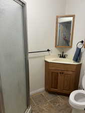 Bathroom featuring a shower stall, vanity, and stone finish floors