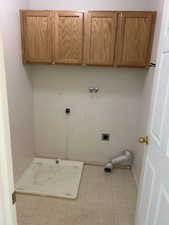 Washroom featuring cabinet space, hookup for an electric dryer, hookup for a washing machine, and light tile patterned floors