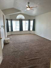 Carpeted spare room with vaulted ceiling, a textured ceiling, and ceiling fan