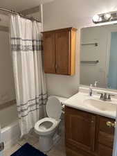 Bathroom featuring light tile patterned floors, vanity, shower / tub combo with curtain, and a textured ceiling
