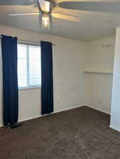 Unfurnished room with a ceiling fan, a textured ceiling, and dark carpet