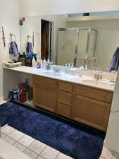 Full bathroom with tile patterned floors, a shower stall, and double vanity