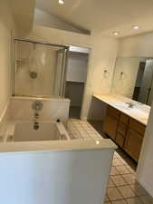Bathroom featuring light tile patterned floors, recessed lighting, double vanity, a shower stall, and a bath