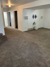 Unfurnished living room featuring dark colored carpet, a textured ceiling, and stairway