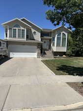 View of front of house with an attached garage, driveway, and a front lawn