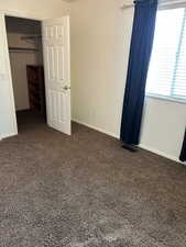 Unfurnished bedroom featuring dark carpet and a walk in closet