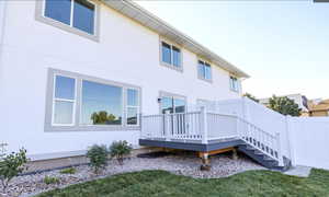 Rear view of house with stucco siding and a wooden deck