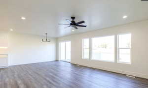 Unfurnished living room with dark wood-type flooring, ceiling fan, a chandelier, and recessed lighting