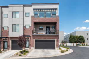 Contemporary house with concrete driveway, stucco siding, and brick siding