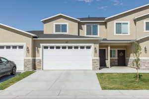 View of front of house featuring stone siding, stucco siding, concrete driveway, roof with shingles, and an attached garage