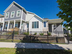 View of front of home featuring board and batten siding, stone siding, a fenced front yard, and a porch