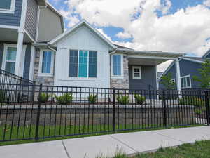 View of front of house featuring stone siding, board and batten siding, a fenced front yard,