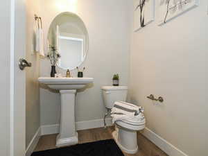 Half bathroom with wood finished floors and toilet