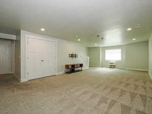 Basement featuring carpet flooring, stairs, a textured ceiling, and recessed lighting