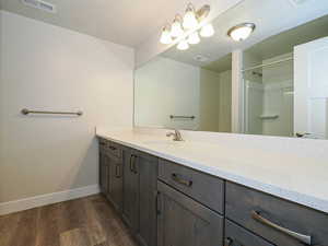 Full bath with vanity, wood finished floors, and a shower