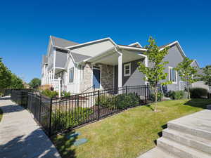 View of side of home with stone siding, a porch, and roof with shingles
