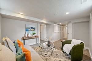 Carpeted living area with a textured ceiling and recessed lighting