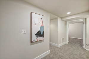 Hall with light colored carpet and recessed lighting